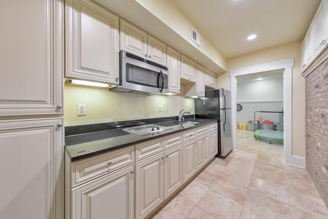 kitchen with brick wall, light tile patterned flooring, sink, and appliances with stainless steel finishes