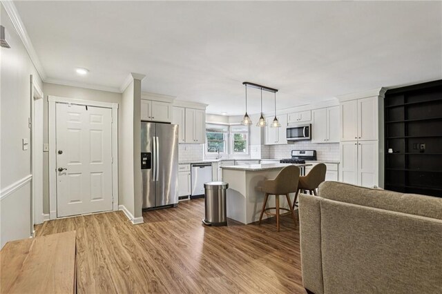208 Hembree Park Ter, Roswell, GA 30076 - kitchen featuring appliances with stainless steel finishes, white cabinetry, light wood-style flooring, a kitchen bar, and ornamental molding