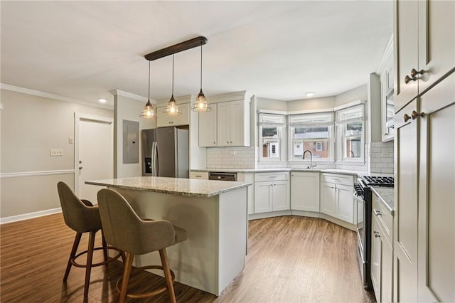 208 Hembree Park Ter, Roswell, GA 30076 - kitchen with appliances with stainless steel finishes, a center island, decorative backsplash, light wood finished floors, and crown molding