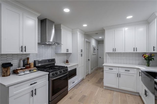 kitchen with white cabinets, wall chimney exhaust hood, and stainless steel range with gas stovetop