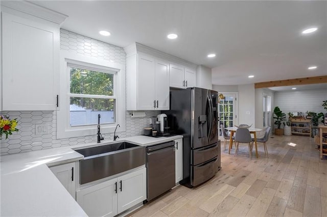 kitchen with white cabinetry, sink, black refrigerator with ice dispenser, light hardwood / wood-style flooring, and stainless steel dishwasher