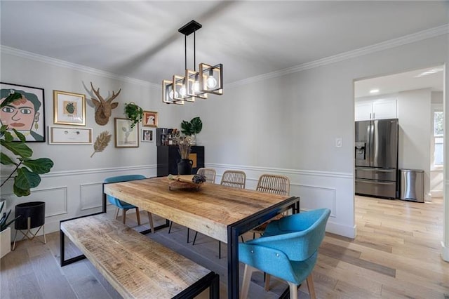 dining area featuring light hardwood / wood-style floors, ornamental molding, and a notable chandelier