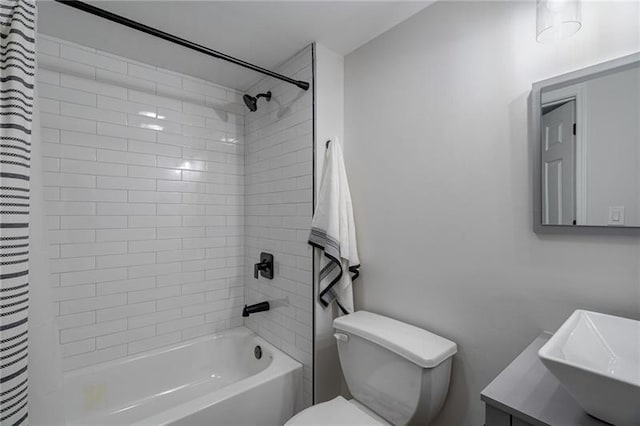 full bathroom featuring vanity, tiled shower / bath combo, and toilet