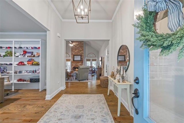 726 Swilling Rd, Eastanollee, GA 30538 - entrance foyer featuring wood finished floors, vaulted ceiling, crown molding, a chandelier, and a brick fireplace