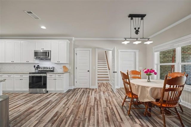 726 Swilling Rd, Eastanollee, GA 30538 - kitchen with appliances with stainless steel finishes, crown molding, white cabinets, tasteful backsplash, and light wood-style floors