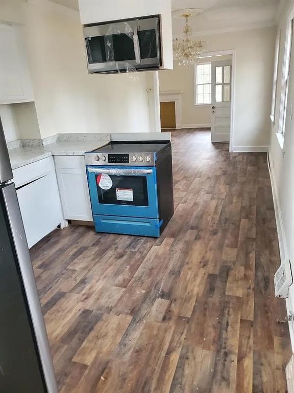 kitchen with white cabinets, dark hardwood / wood-style flooring, stainless steel appliances, and an inviting chandelier