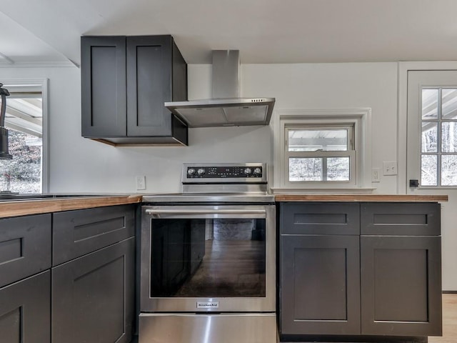 kitchen with wooden counters, wall chimney exhaust hood, and stainless steel electric range oven