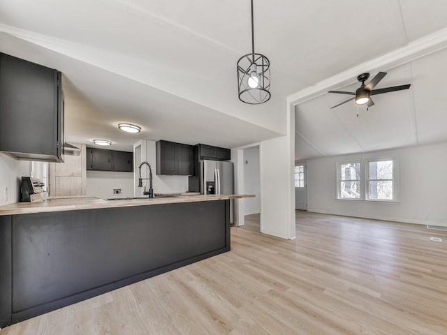 kitchen featuring light hardwood / wood-style flooring, ceiling fan, decorative light fixtures, vaulted ceiling, and kitchen peninsula