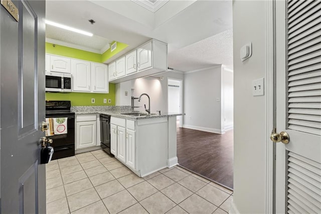 kitchen with kitchen peninsula, ornamental molding, sink, black appliances, and white cabinetry