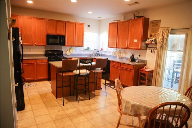 kitchen with black appliances, a center island, sink, and a breakfast bar area