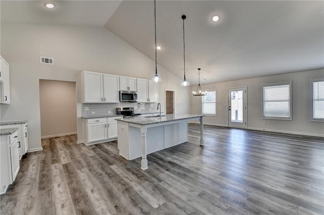 kitchen with sink, a breakfast bar, stainless steel appliances, white cabinets, and a center island with sink