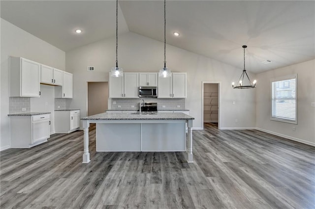 kitchen with light stone counters, sink, an island with sink, and white cabinets