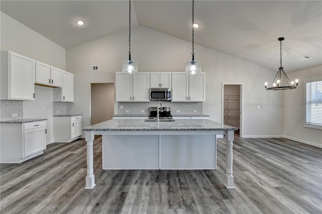 kitchen with white cabinetry, light stone countertops, and pendant lighting