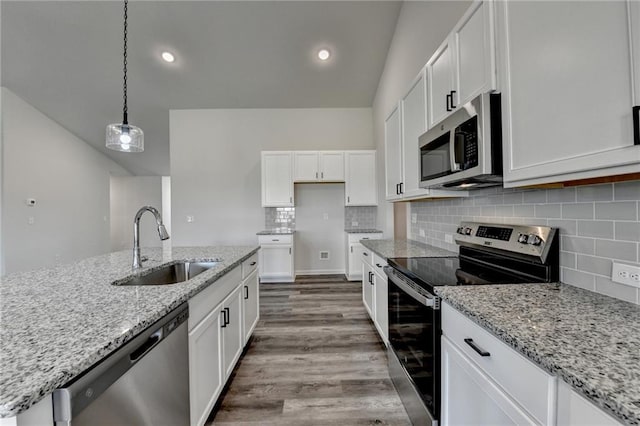 kitchen with pendant lighting, white cabinetry, sink, light stone counters, and stainless steel appliances