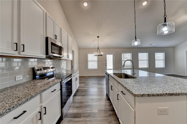 kitchen with an island with sink, sink, white cabinets, hanging light fixtures, and stainless steel appliances