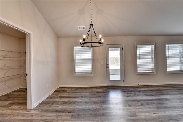 unfurnished dining area featuring vaulted ceiling, an inviting chandelier, and dark hardwood / wood-style flooring