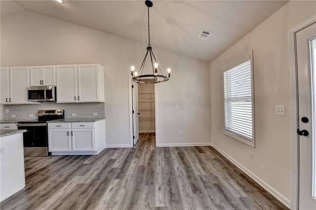 kitchen featuring vaulted ceiling, white cabinetry, appliances with stainless steel finishes, and decorative light fixtures