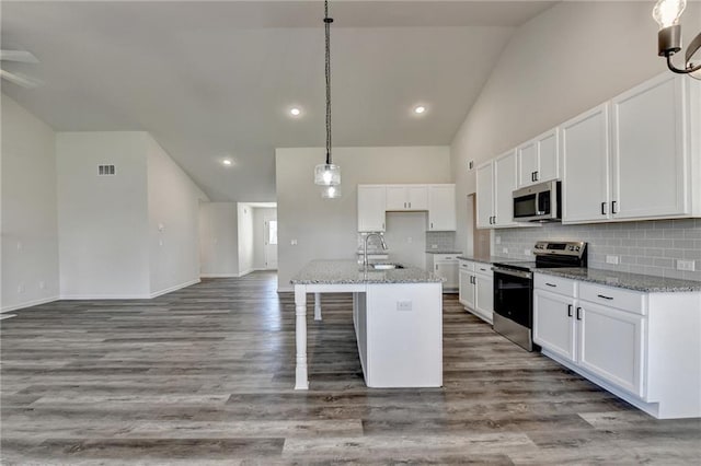 kitchen featuring appliances with stainless steel finishes, an island with sink, sink, white cabinets, and light stone counters