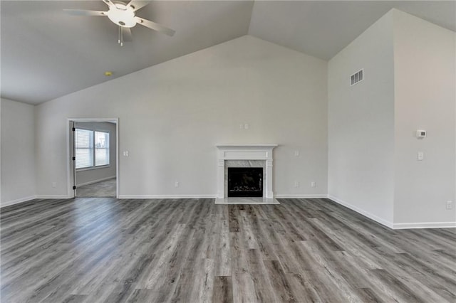 unfurnished living room featuring vaulted ceiling, hardwood / wood-style floors, ceiling fan, and a high end fireplace