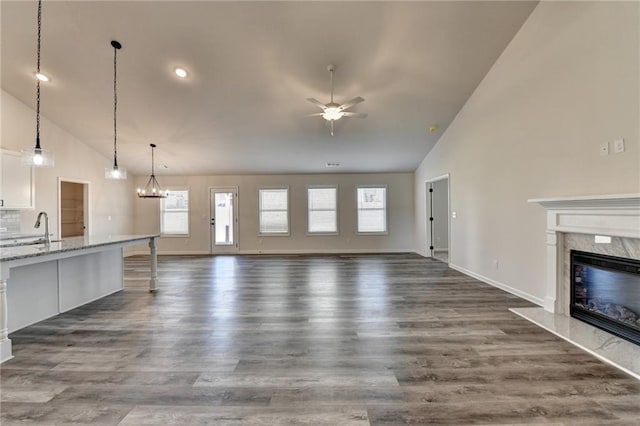 unfurnished living room featuring dark wood-type flooring, sink, high vaulted ceiling, ceiling fan, and a premium fireplace