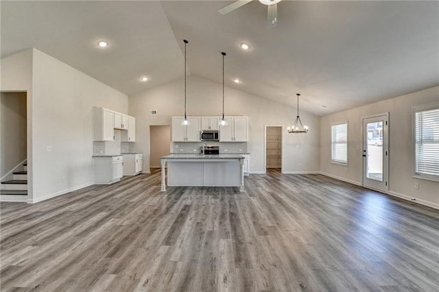 kitchen featuring pendant lighting, tasteful backsplash, white cabinets, and a center island with sink