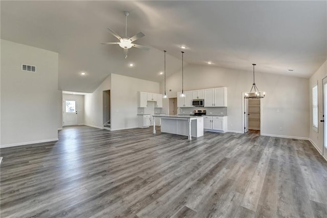 unfurnished living room with sink, ceiling fan with notable chandelier, high vaulted ceiling, and hardwood / wood-style flooring