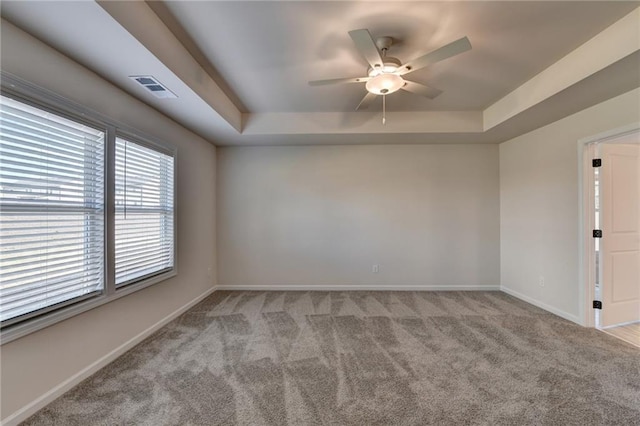 carpeted empty room featuring a raised ceiling and ceiling fan