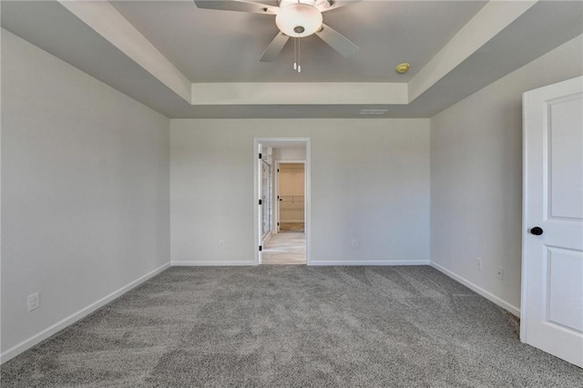 carpeted spare room featuring ceiling fan and a tray ceiling