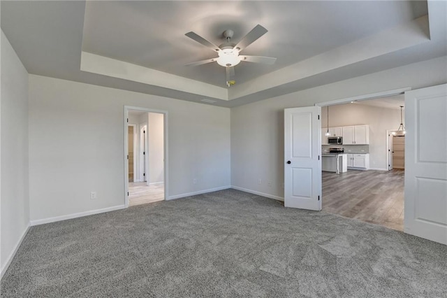 carpeted empty room featuring ceiling fan and a tray ceiling