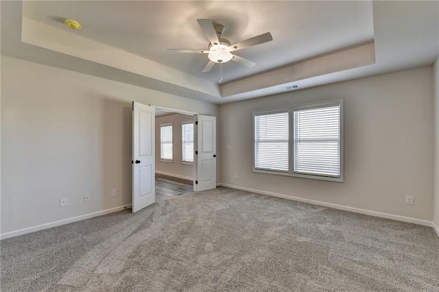 spare room featuring ceiling fan, carpet flooring, and a raised ceiling