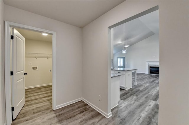 corridor with hardwood / wood-style flooring and vaulted ceiling