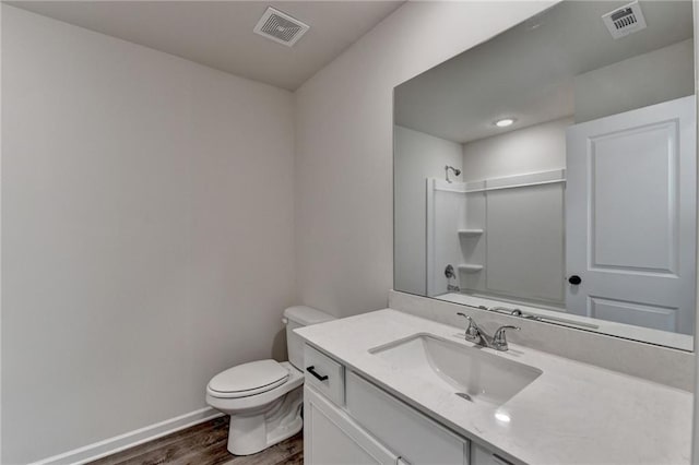 bathroom featuring vanity, hardwood / wood-style flooring, toilet, and a shower