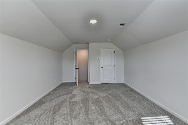 bonus room with vaulted ceiling and light colored carpet