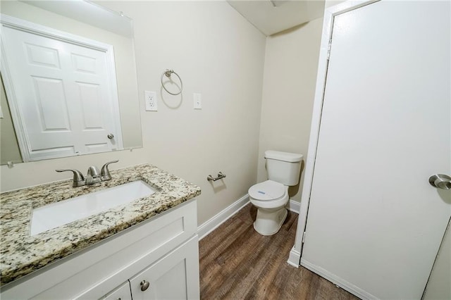 bathroom featuring wood finished floors, toilet, vanity, and baseboards