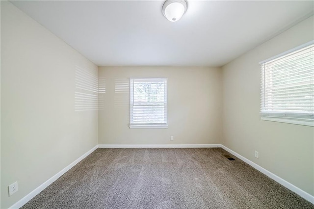 carpeted spare room with visible vents and baseboards