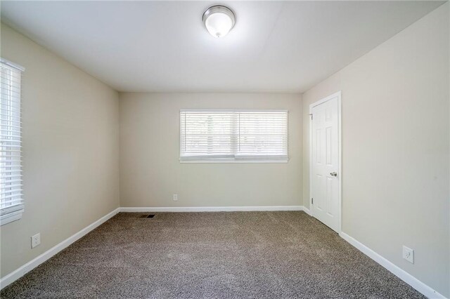 carpeted spare room featuring visible vents and baseboards