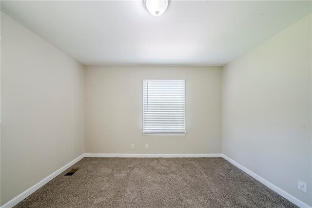 carpeted spare room with visible vents and baseboards