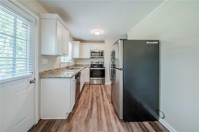 kitchen with white cabinetry, stainless steel appliances, light wood-style flooring, and a sink