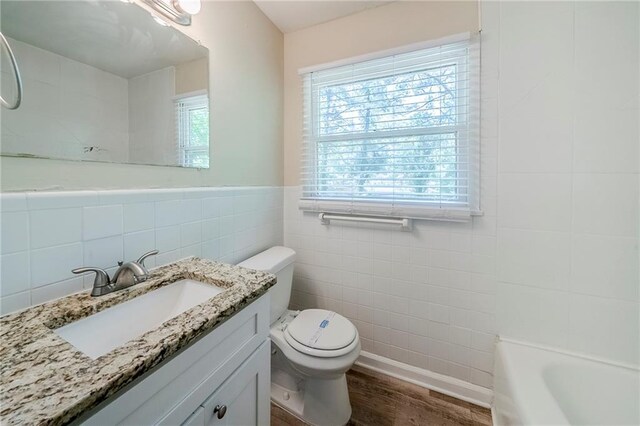 bathroom with wood finished floors, toilet, vanity, and tile walls
