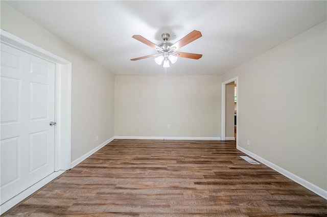 spare room featuring wood finished floors, ceiling fan, and baseboards