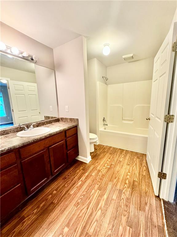 full bathroom with toilet, vanity, wood-type flooring, and bathing tub / shower combination