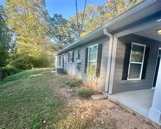 view of property exterior featuring central AC unit and a lawn