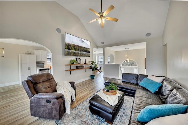 living room featuring light hardwood / wood-style floors, high vaulted ceiling, and ceiling fan