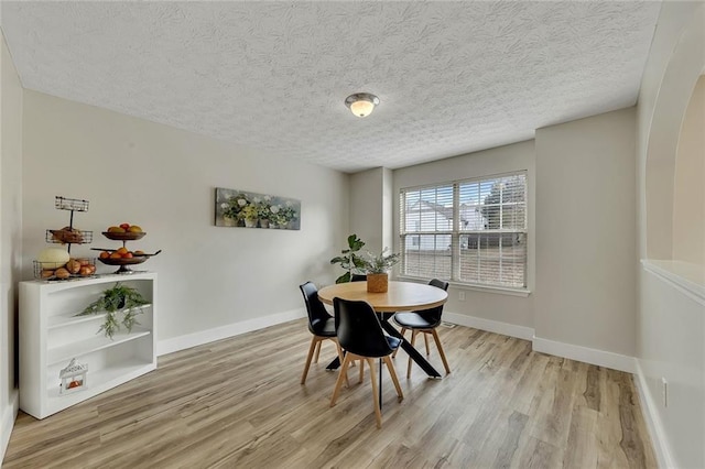 dining area featuring a textured ceiling and light hardwood / wood-style flooring