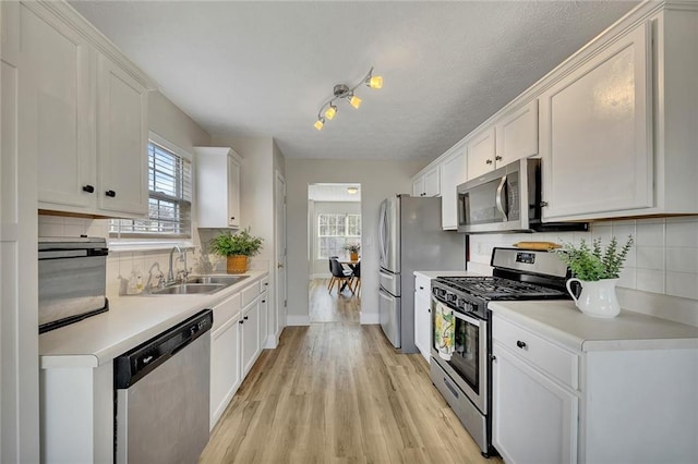 kitchen featuring sink, white cabinets, light wood-type flooring, and appliances with stainless steel finishes