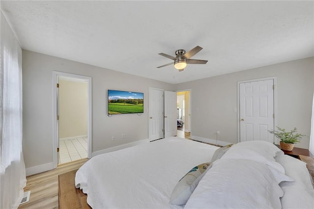 bedroom with ceiling fan, light wood-type flooring, and ensuite bath