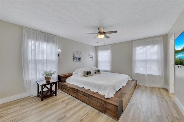 bedroom with a textured ceiling, light hardwood / wood-style flooring, and ceiling fan