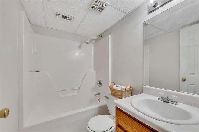 full bathroom featuring shower / washtub combination, a drop ceiling, vanity, and toilet