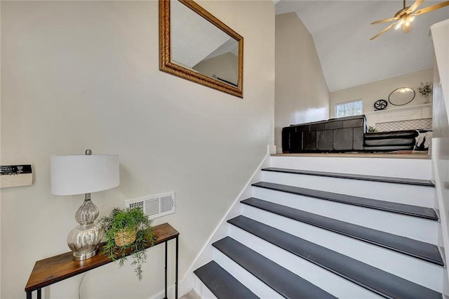 staircase featuring ceiling fan and lofted ceiling