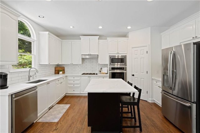 4108 Wyndam Hill Dr, Suwanee, GA 30024 - kitchen with appliances with stainless steel finishes, white cabinets, a center island, tasteful backsplash, and dark wood-style floors
